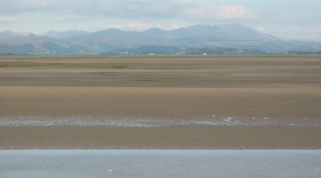 misty mountins in the distance across a sandy bay